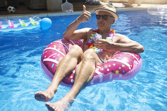 An older person in a floatation device in swimming pool.