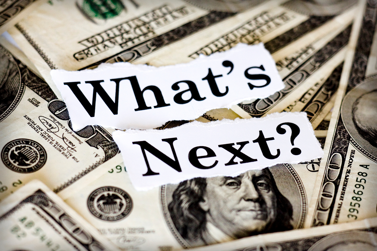 The words What's Next? cut out from a magazine and placed over a pile of $100 bills.