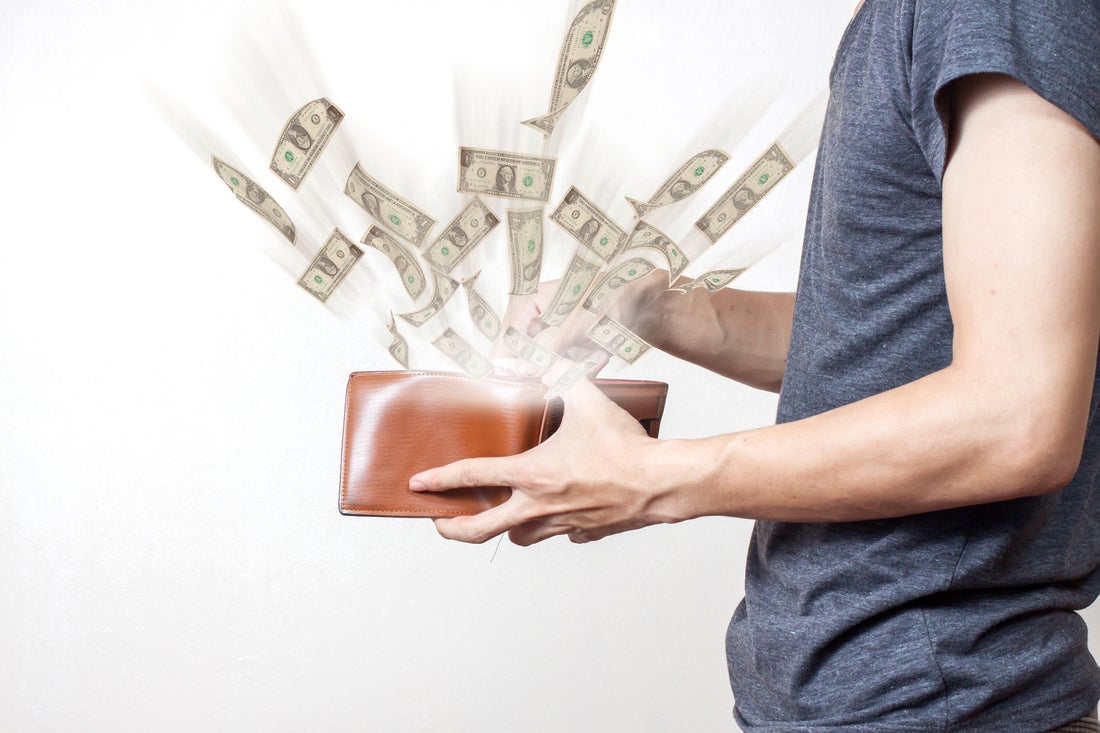 Person holding wallet with cash flying out of it.