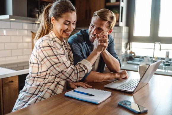 2 people high-fiving with a computer.