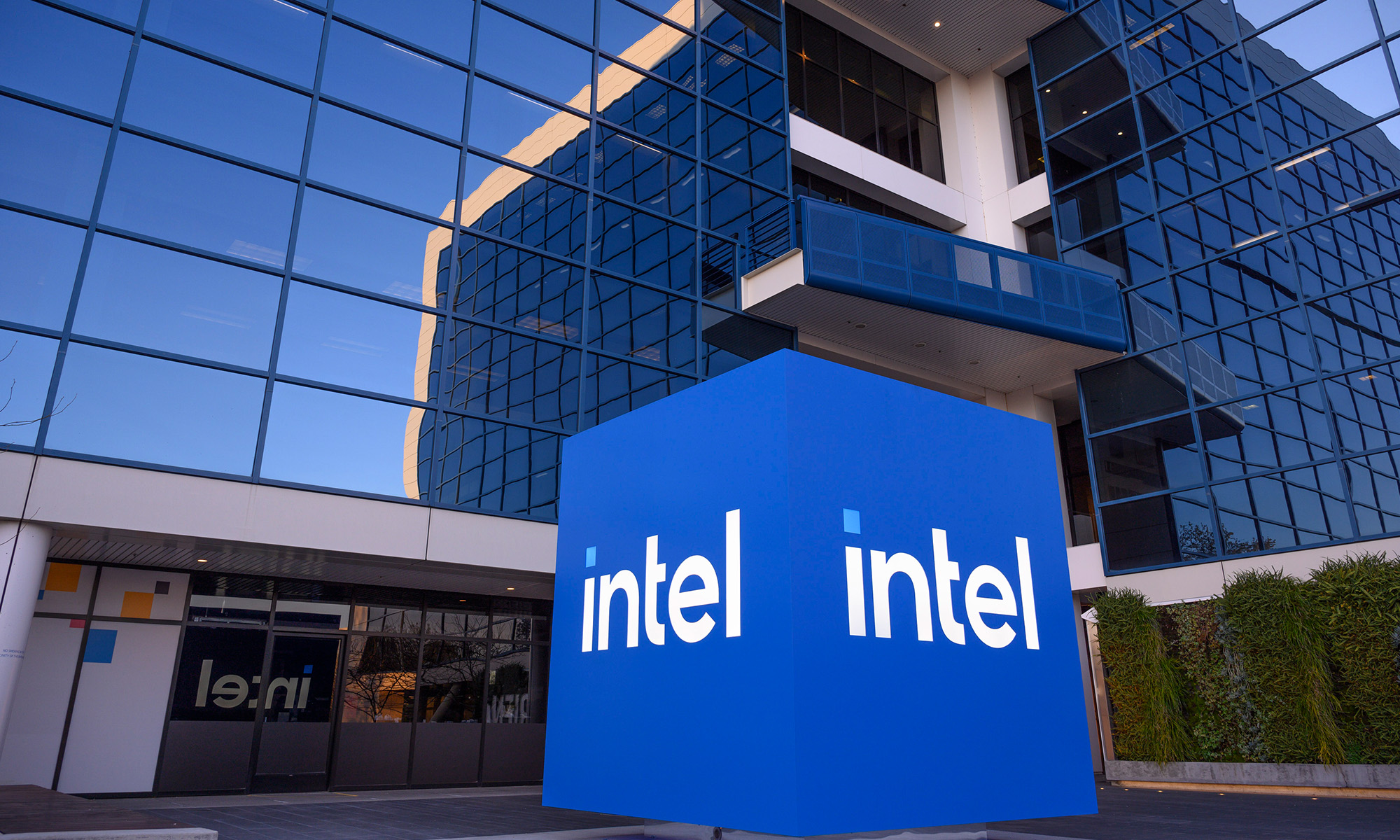 Cube with Intel logo on it outside of a tall glass building.