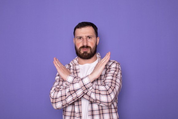 A person crosses their arms as if saying no or stop.