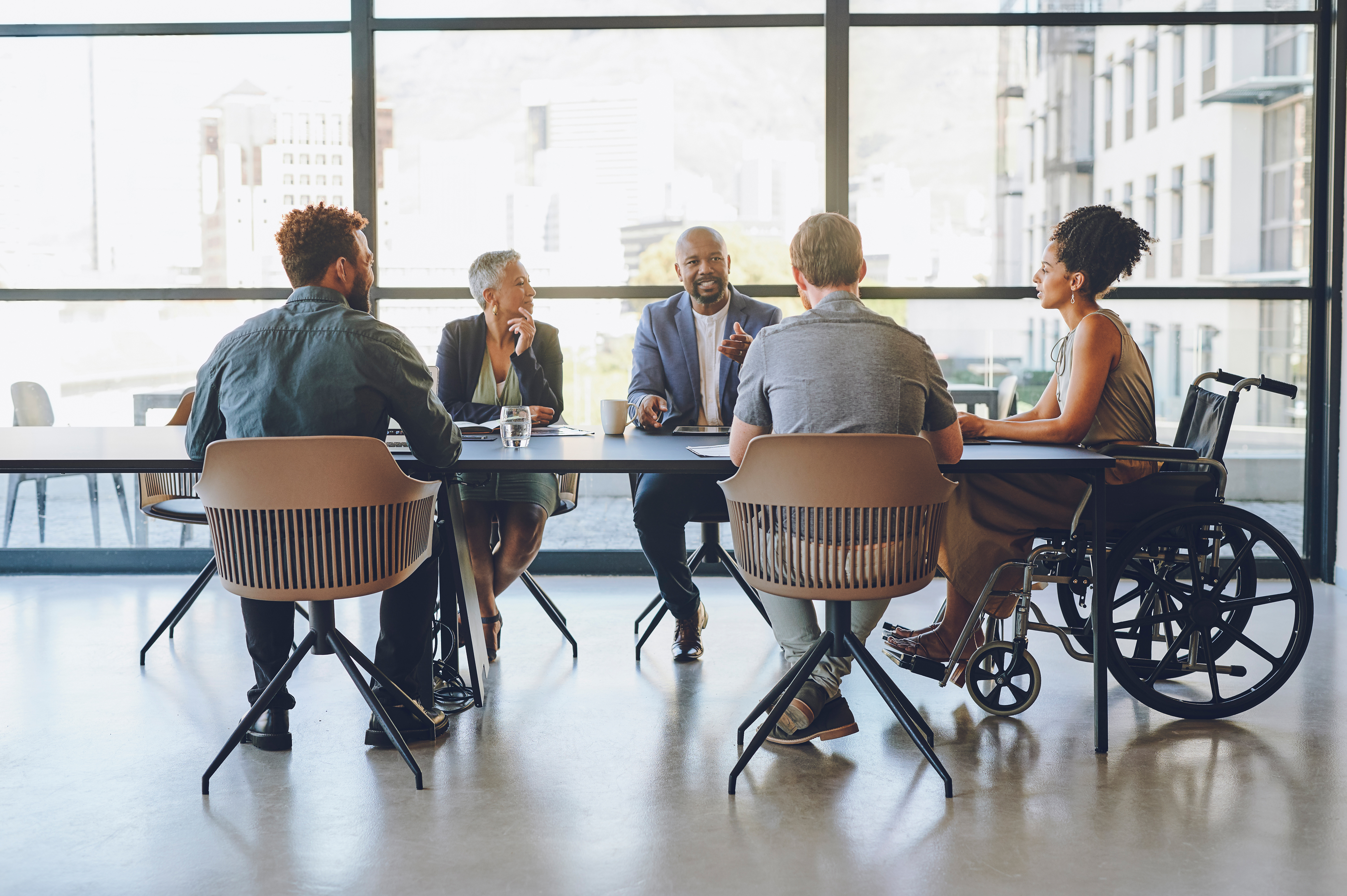 23_11_07 A group of people in a meeting room talking at a table _MF Dload GettyImages-1425293645