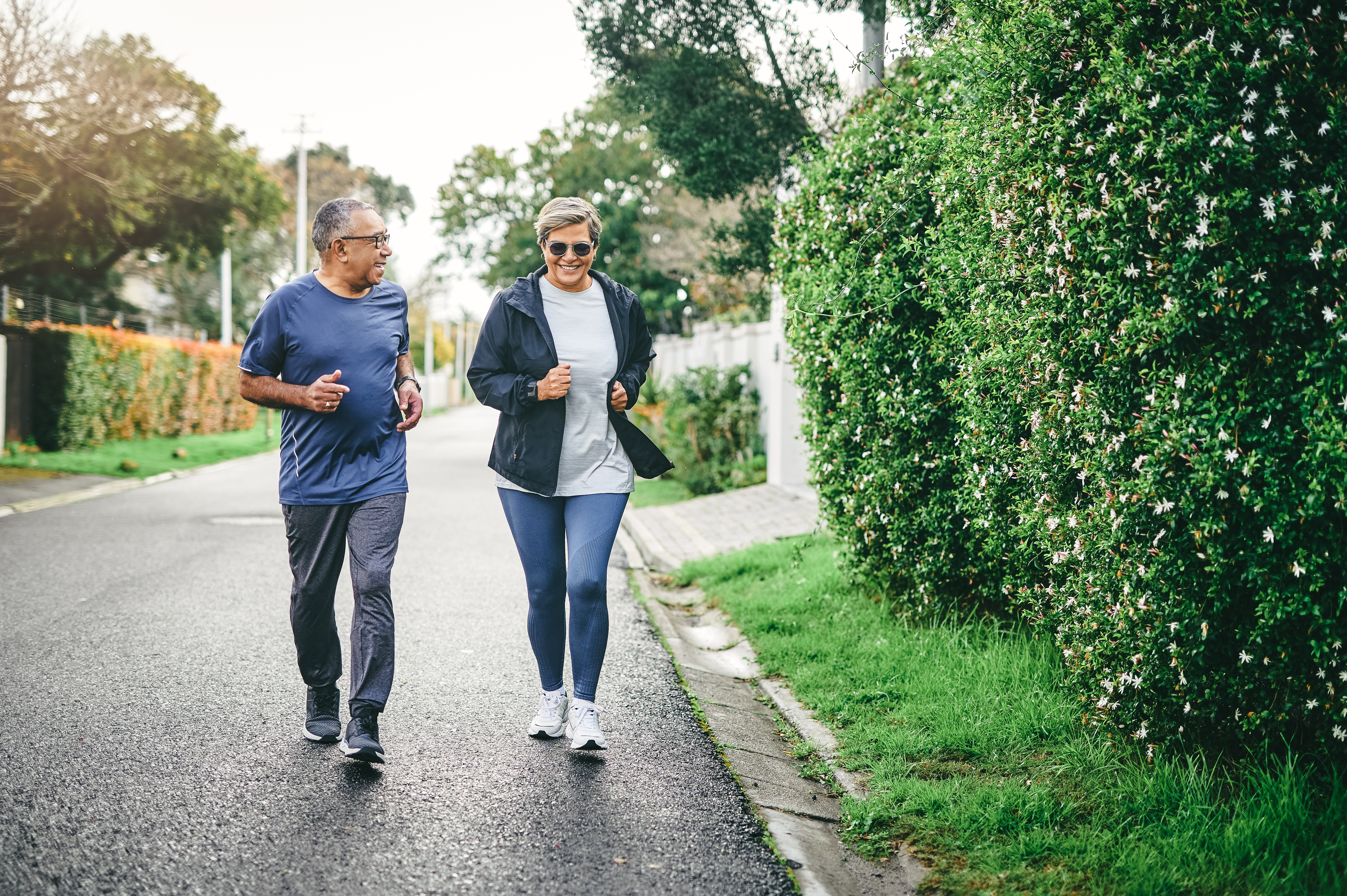 Two people jogging outside on a road.