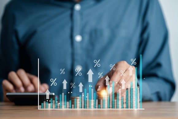 A person working on a calculator with images of bar graphs superimposed.