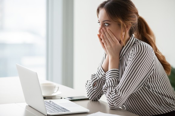 A person with a shocked expression looking at a computer.