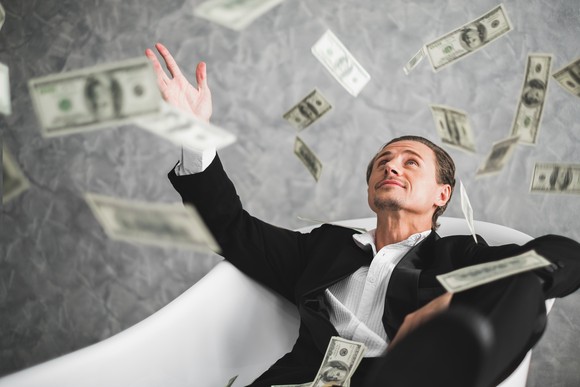 A person in a suit throws cash into the air.