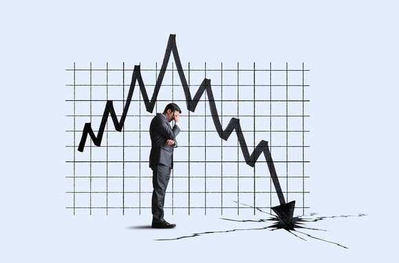 A person standing in front of a large graph with an arrow crashing into the ground.