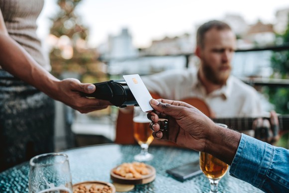 Person paying with tap card at a restaurant.
