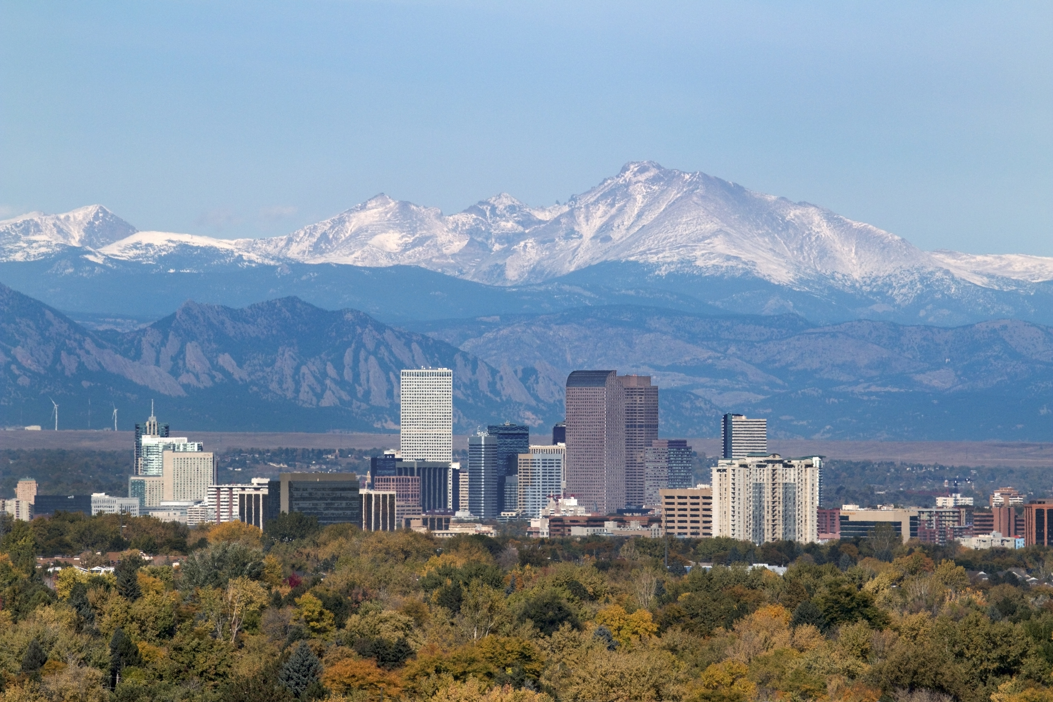 A city is shown, in front of the snowy Rocky Mountains.