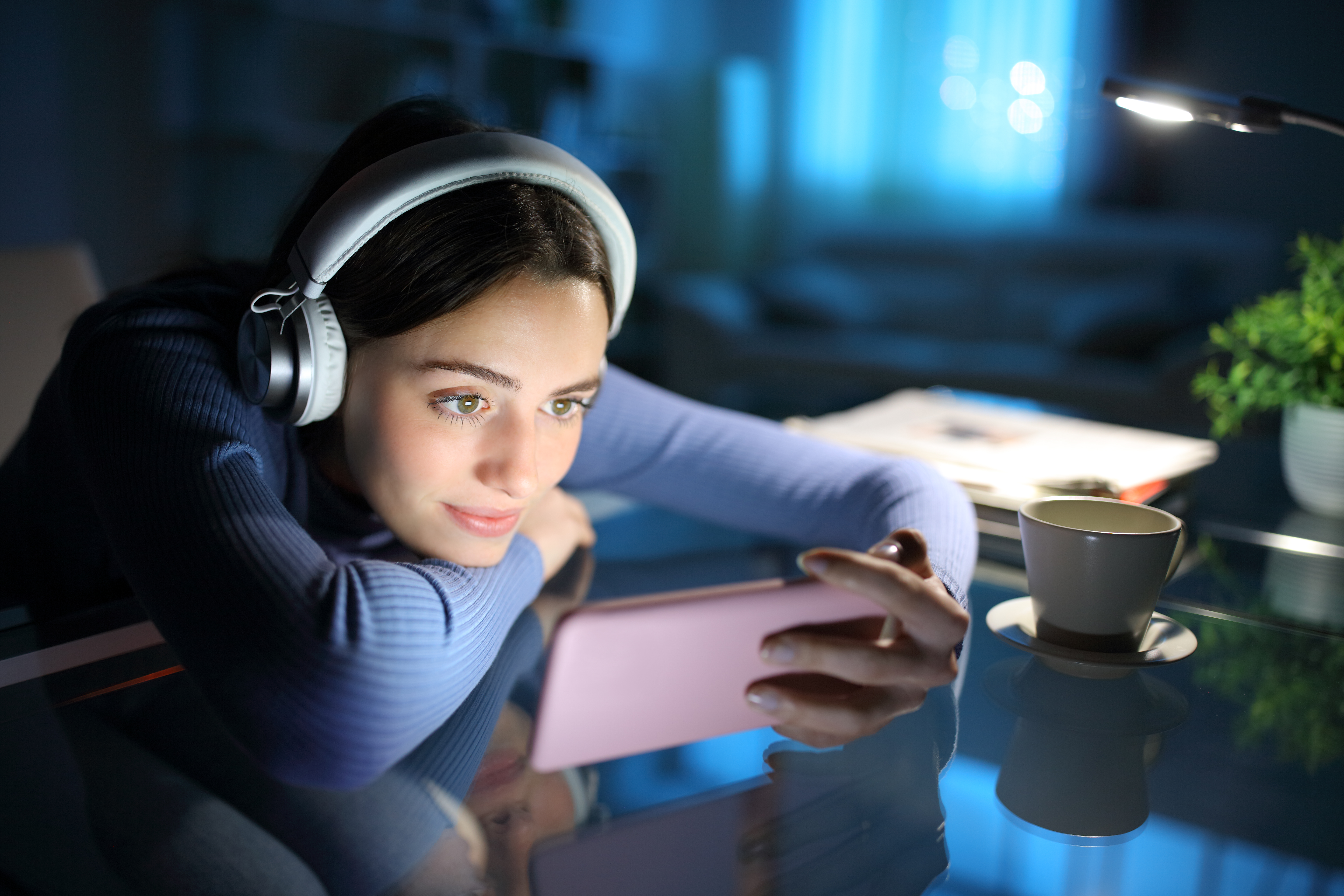 A person looks at phone while wearing headphones.