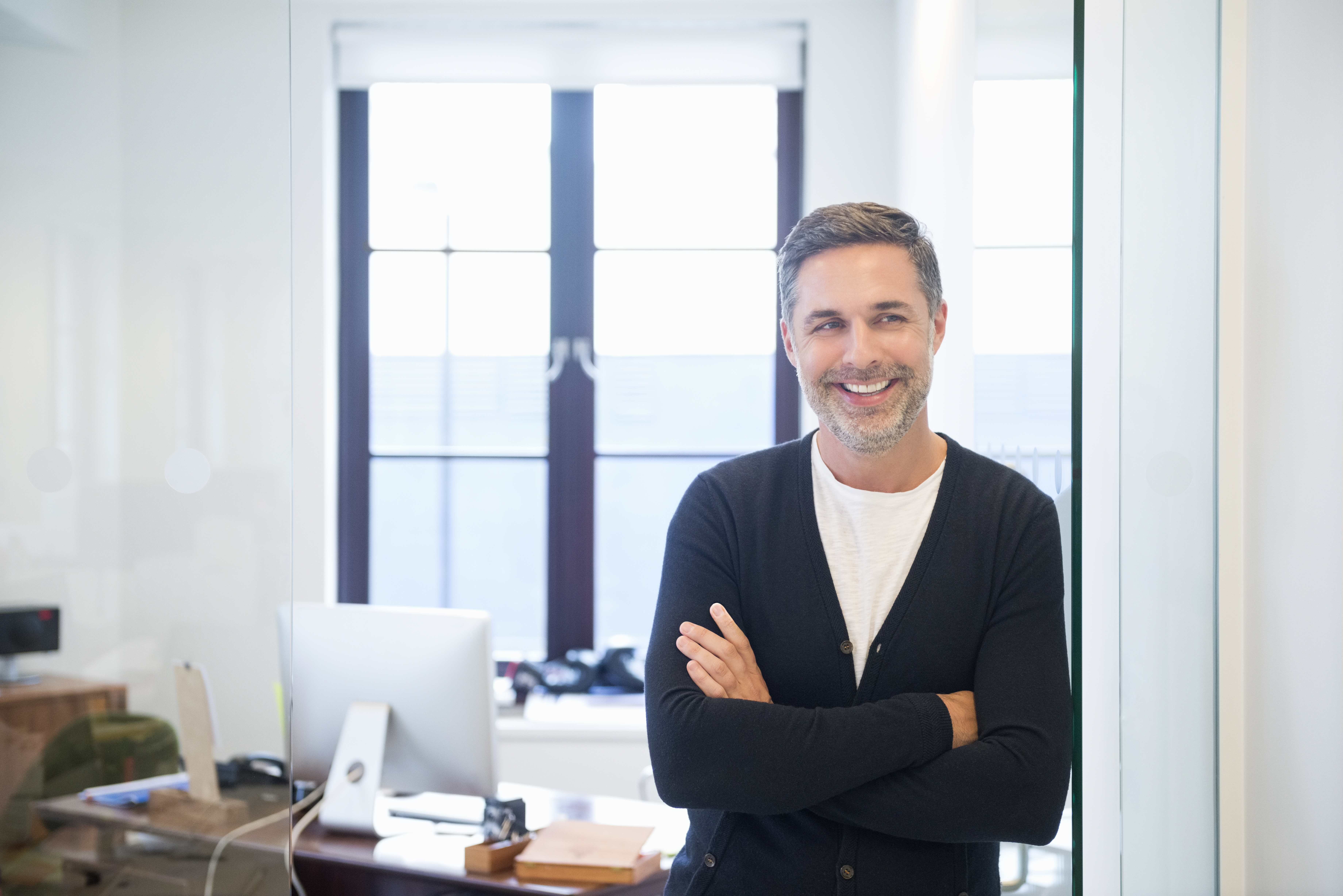 A smiling person standing in front of a desk.
