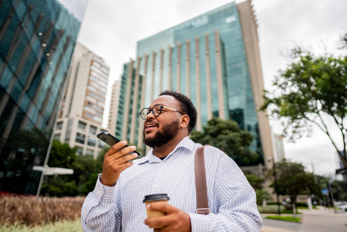 Person holding a cup of coffee and speaking into a phone.