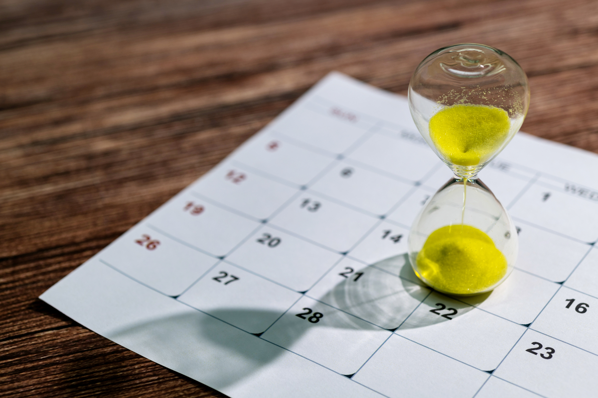 An hourglass sitting on a calendar.