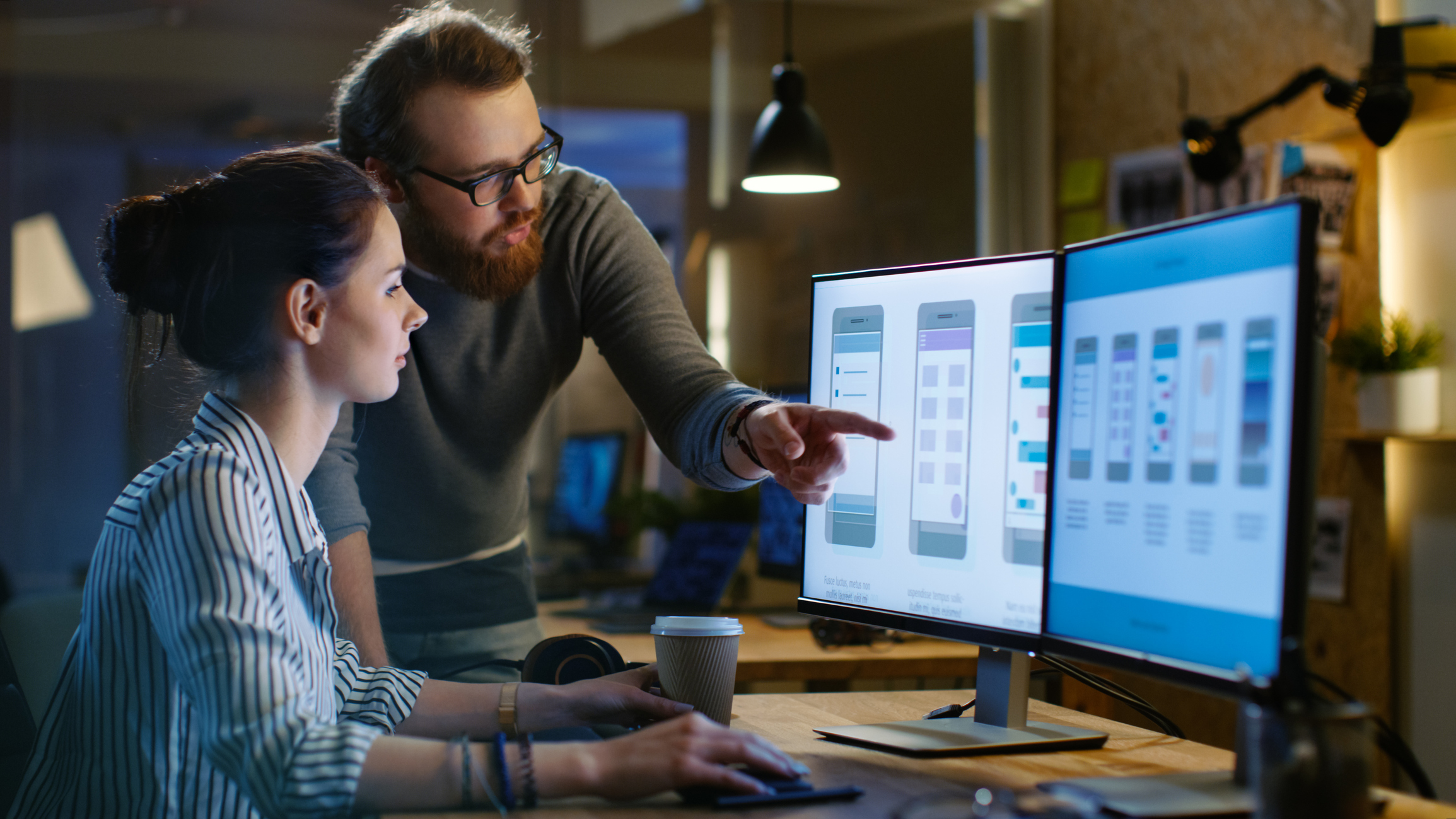 Two user interface designers work together at a workstation.