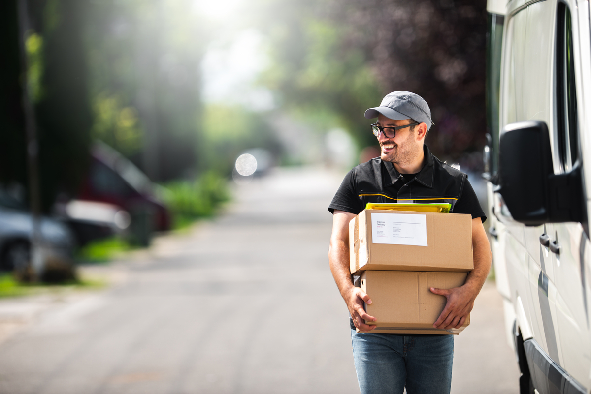 A delivery person smiles while carrying packages.
