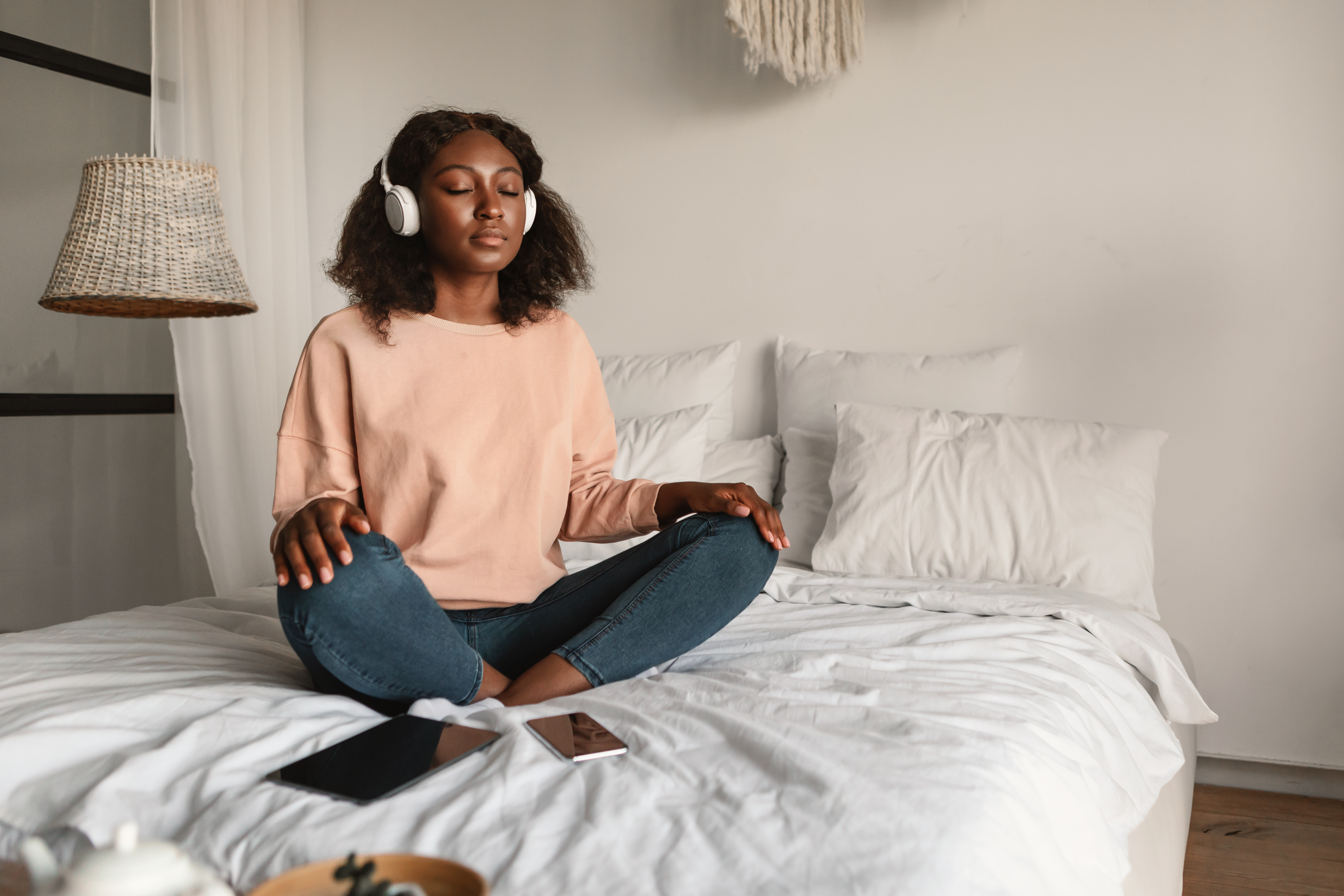 Person sitting on a bed wearing headphones.