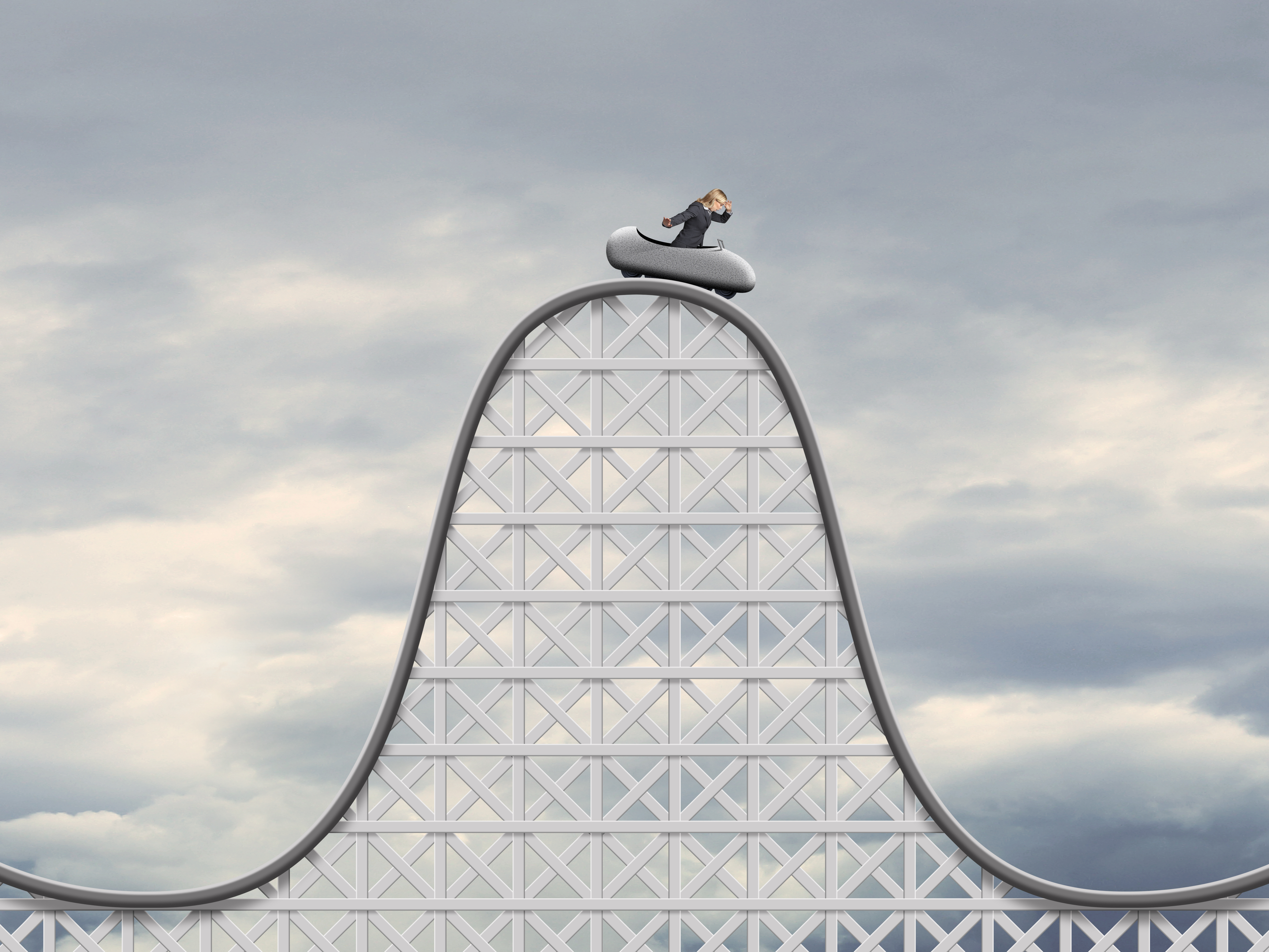 A person at the peak of a roller coaster, preparing for a rapid descent