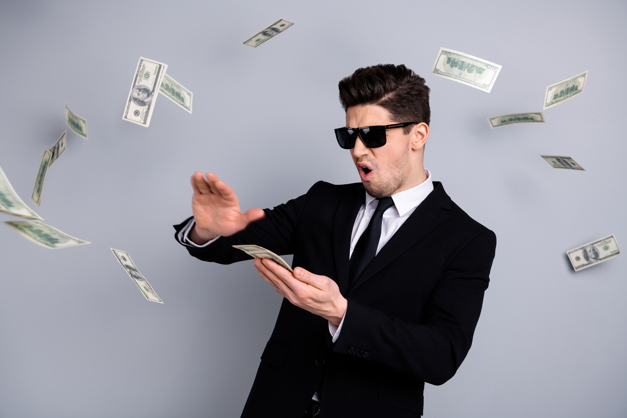 Cool dude in a black suit and shades peeling off $100 bills