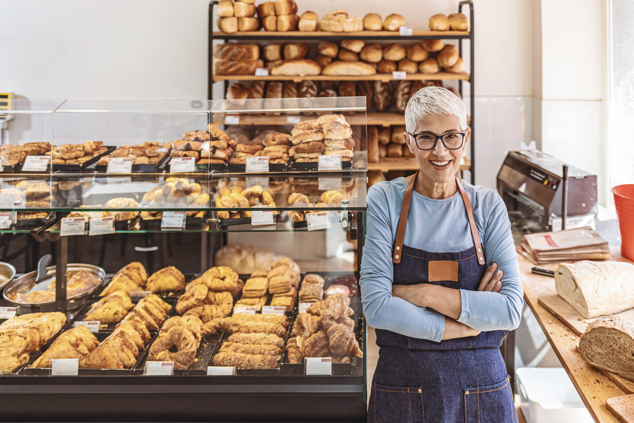 A person in an apron standing in a bakery.