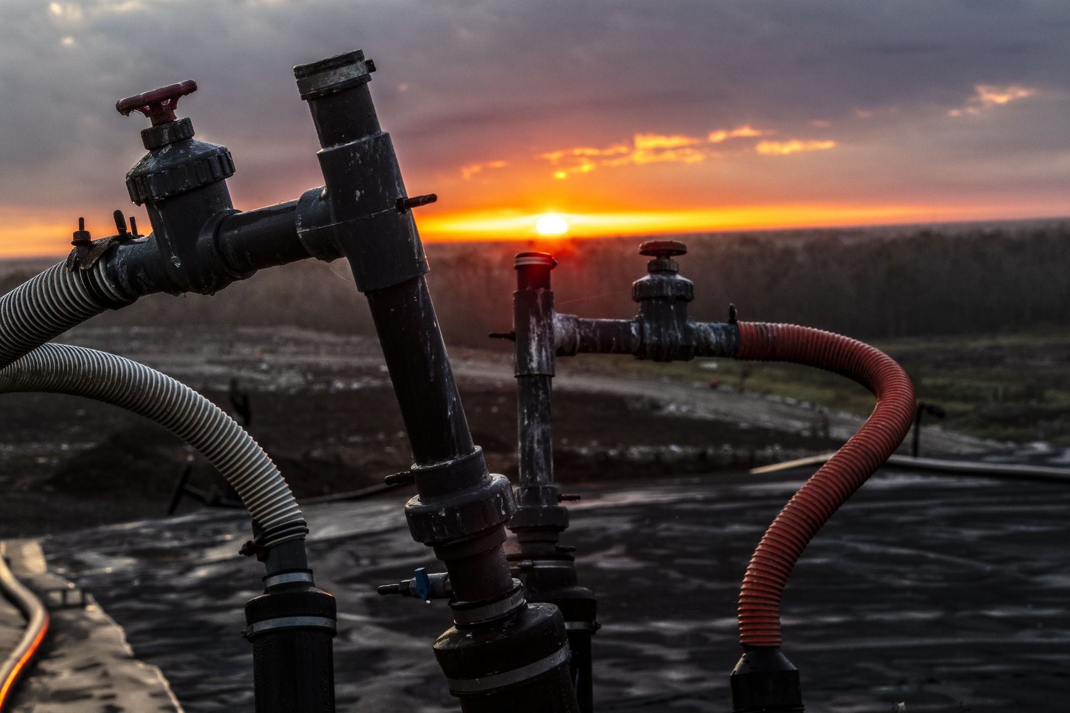 Methane piples at a landfill with the sun setting in the background.