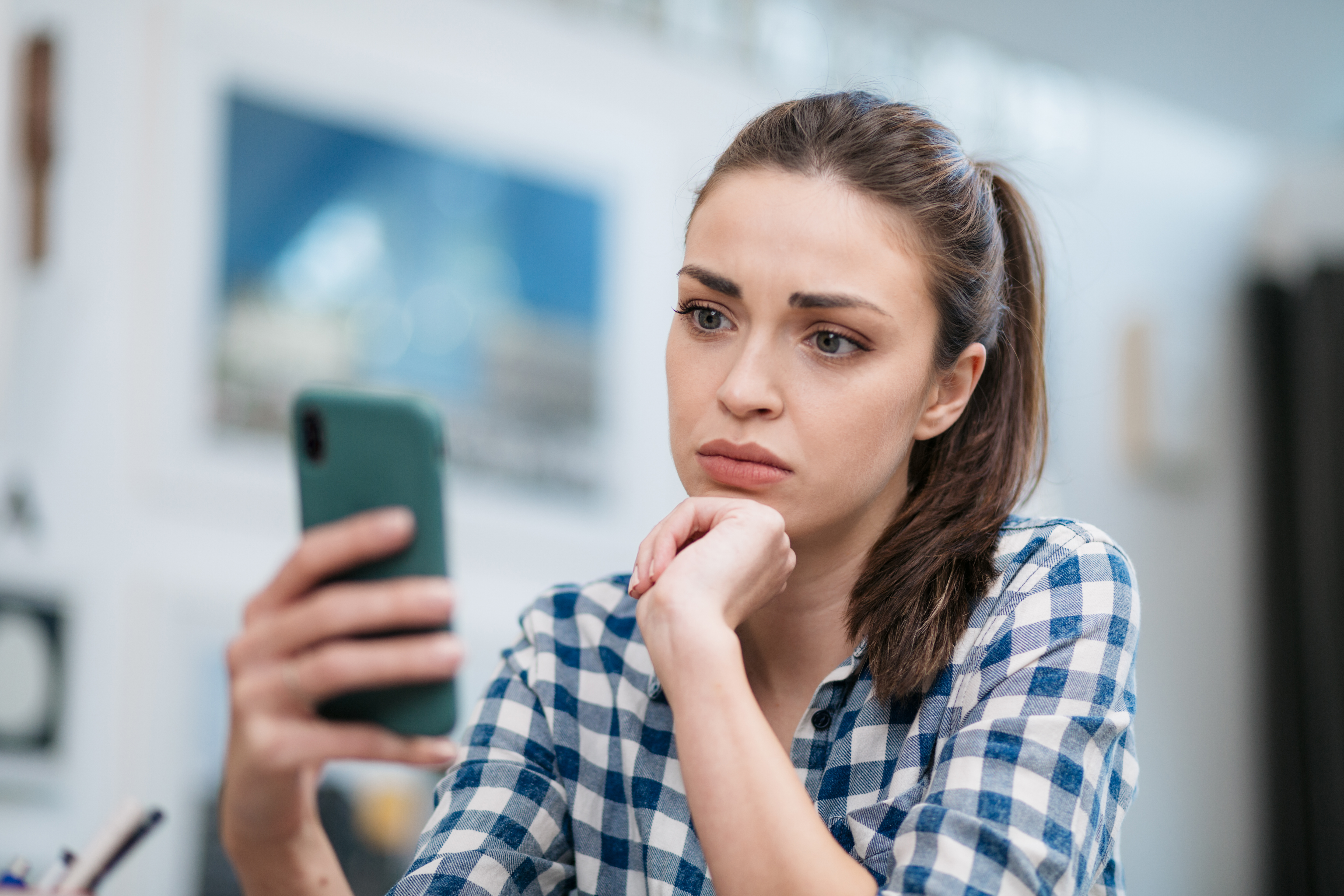 A person looking at their smartphone with a blank facial expression