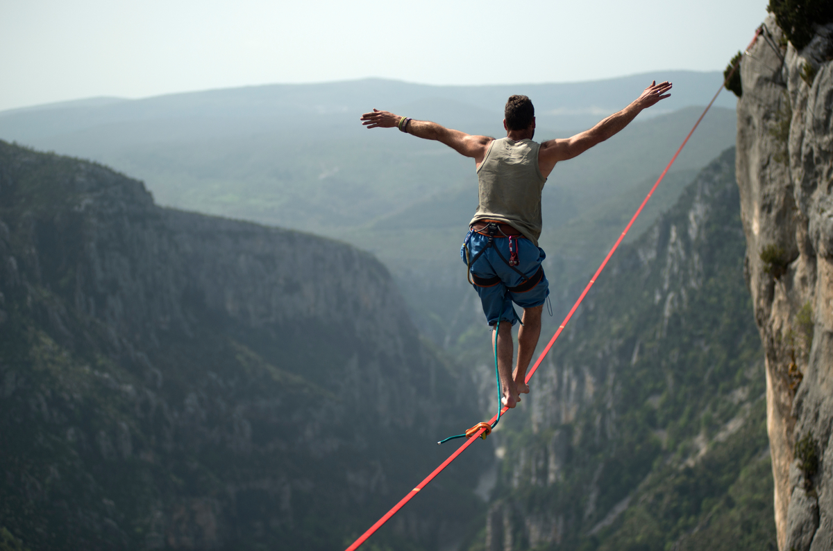 GettyImages-man walking on a tightrope over a canyon