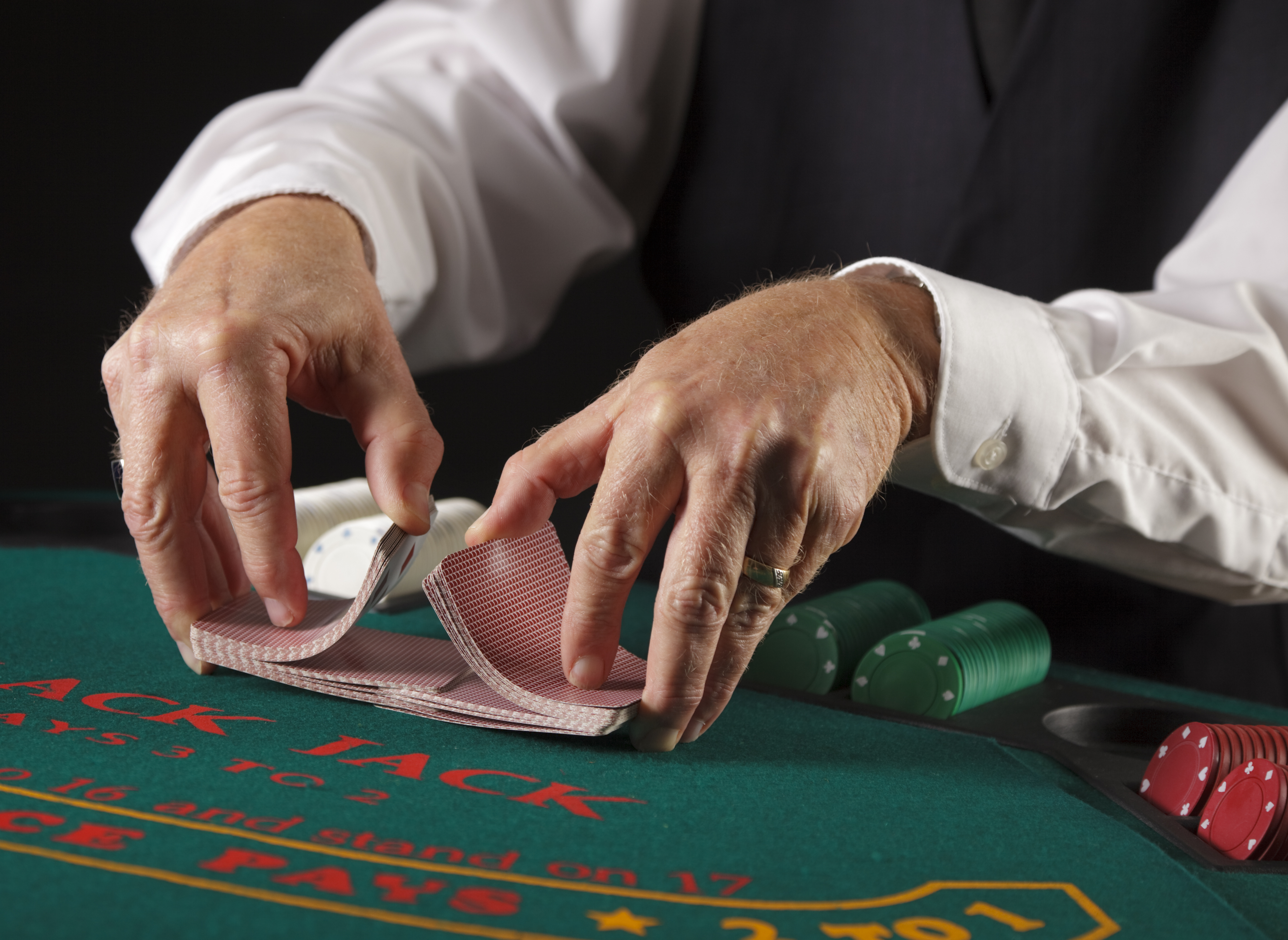 Hands of a dealer shuffling cards at a gambling table