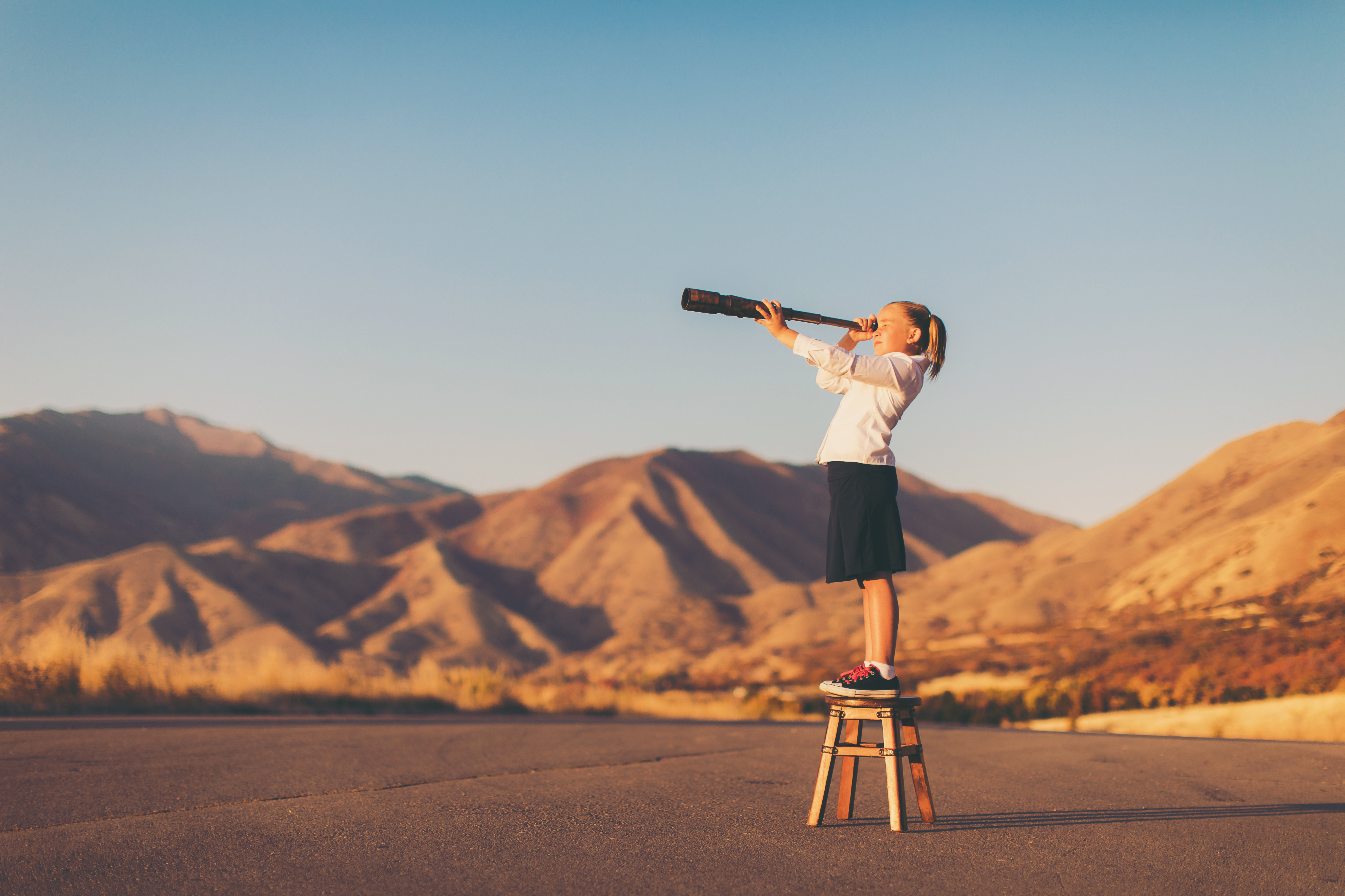A child looking into the distance with a telescope.