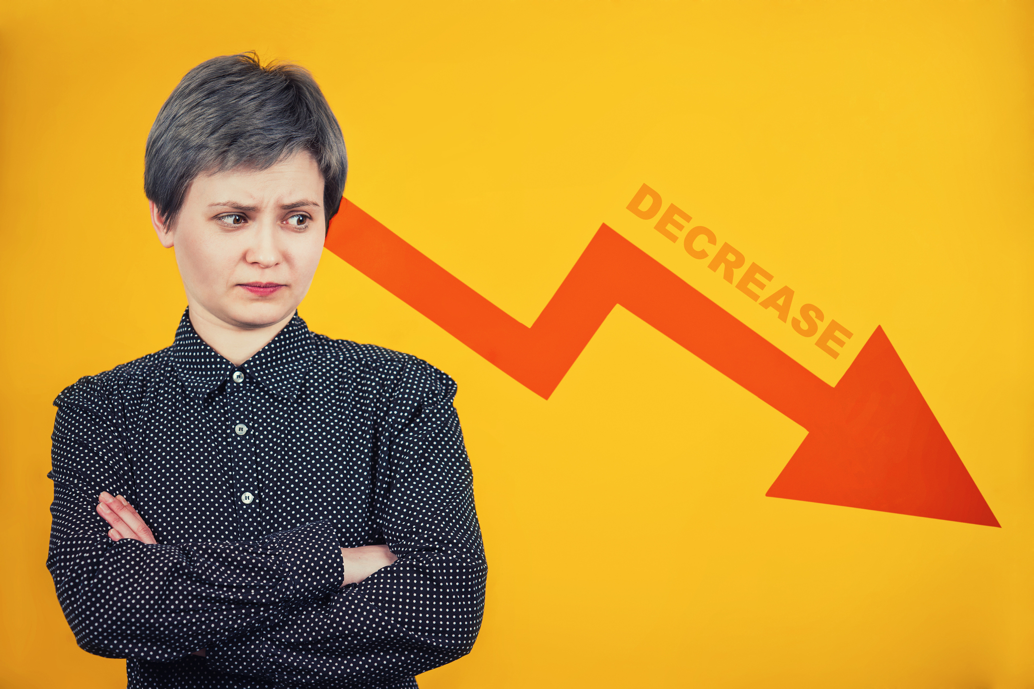 Lady looks askance at a red stock arrow going down.