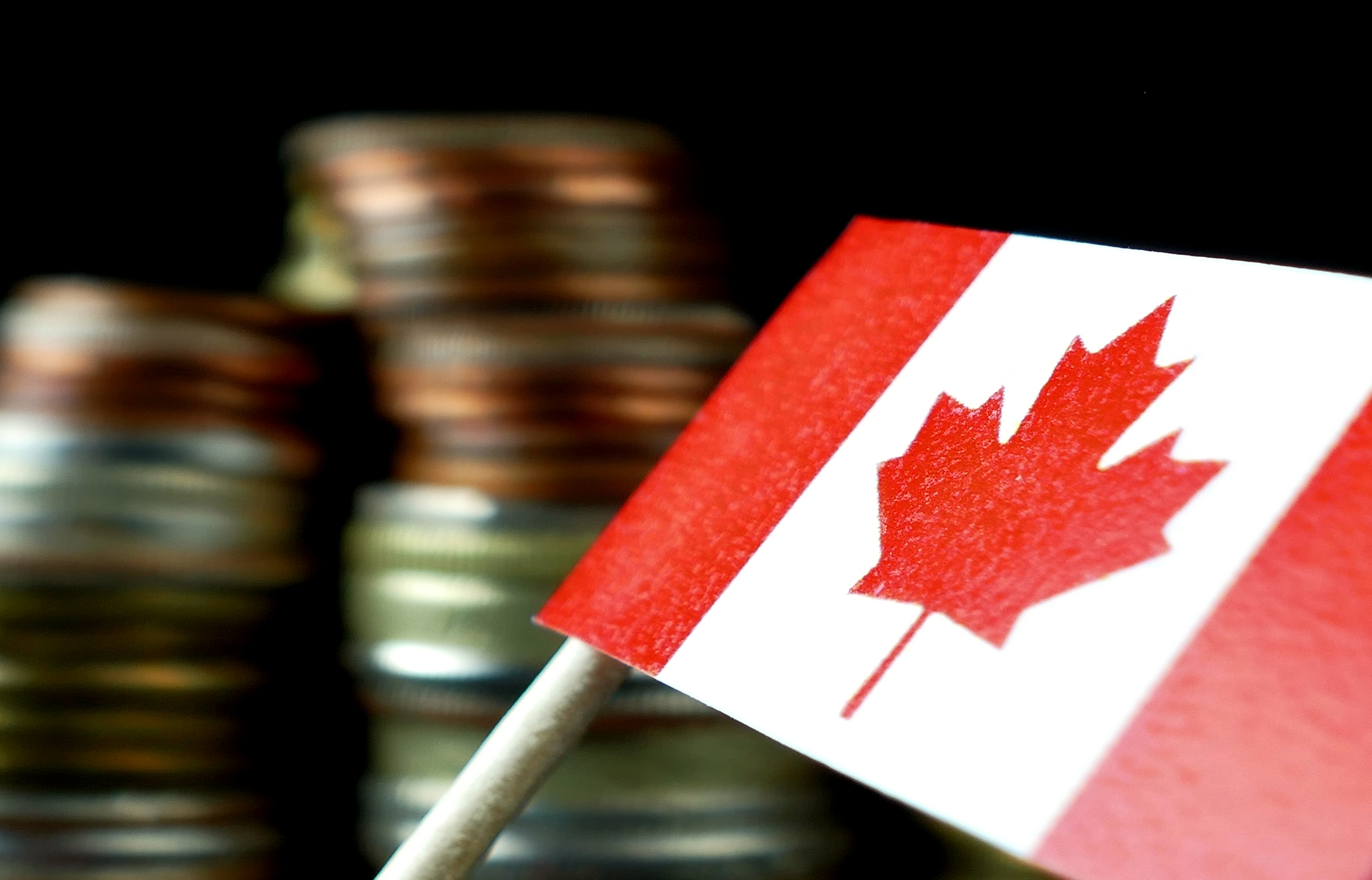 A small Canadian flag with coins in the background