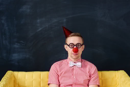 Unhappy clown sitting on a couch. Joke. April Fools