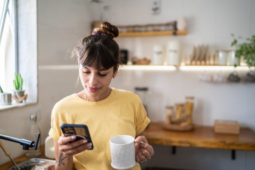 using iphone drinking coffee in kitchen