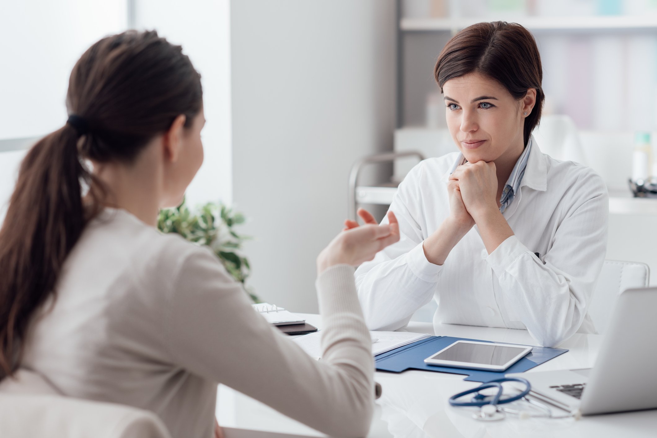 Two women conversing across a desk in an apparent medical setting