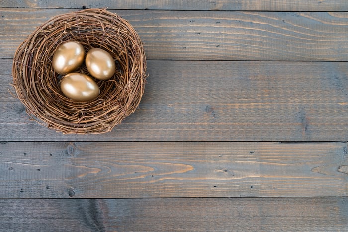 Nest on wooden table with three golden eggs in it