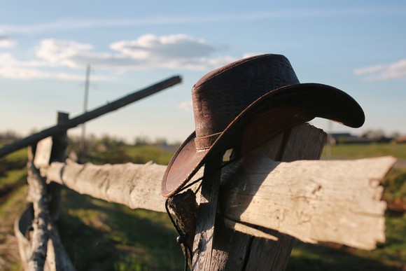 A cowboy hat hanging on a fence post