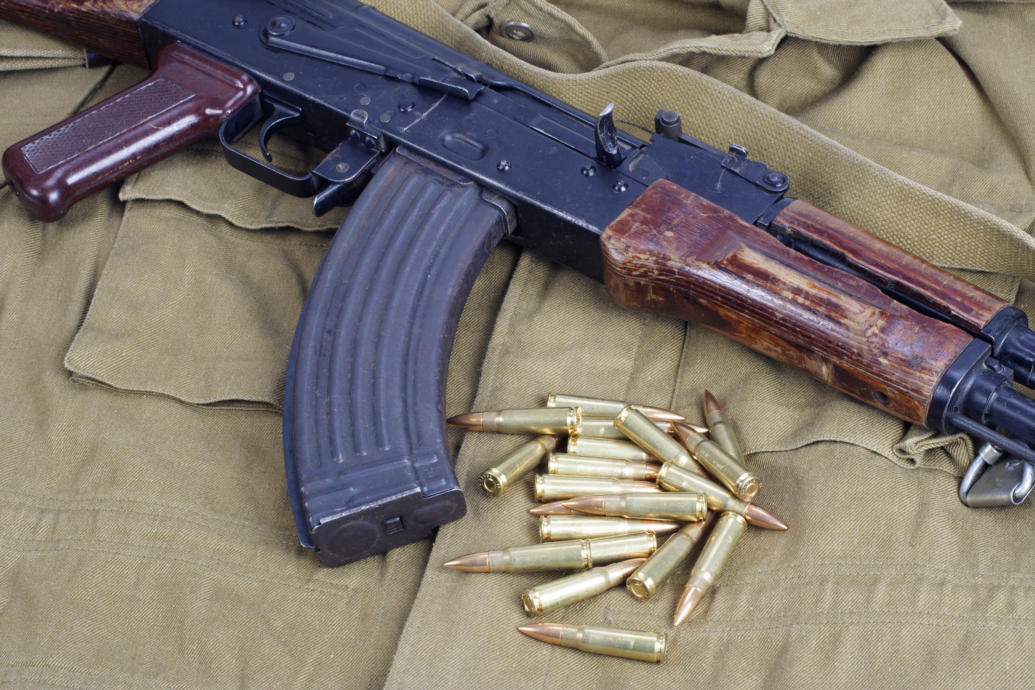 AK-47 and bullets laying on top of a khaki uniform