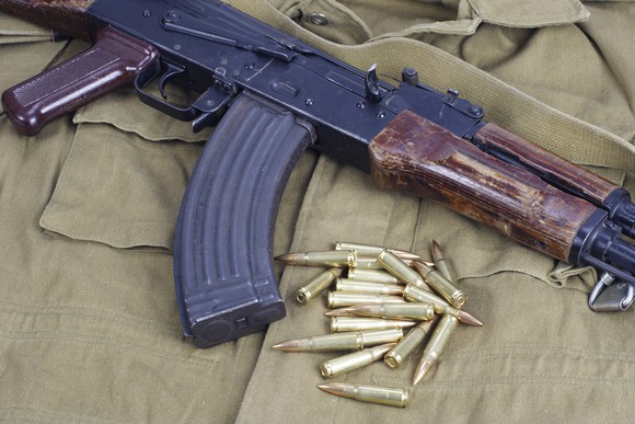 AK-47 and bullets laying on top of a khaki uniform