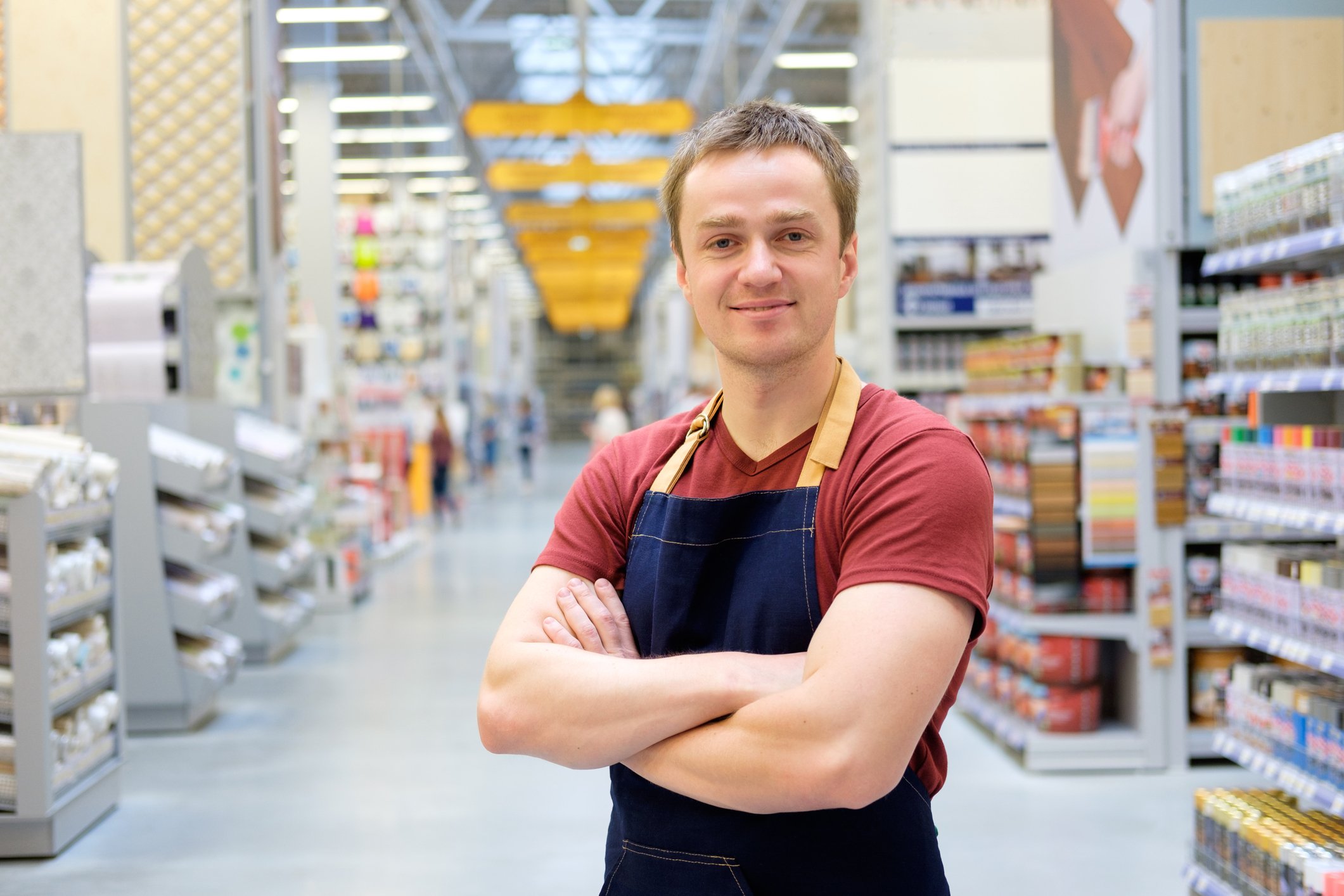 An aproned employee stands in the aisle of a warehouse store.
