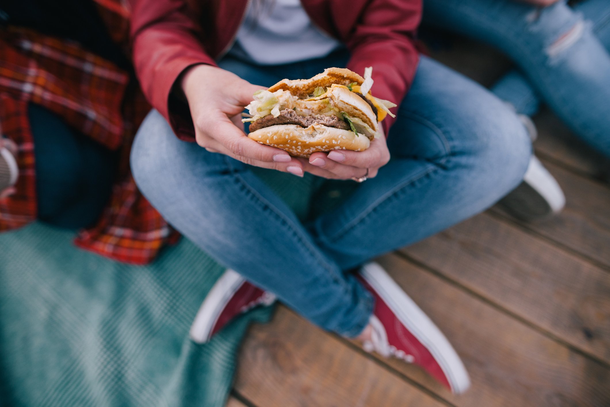 A burger in a woman's hands, with one bite taken