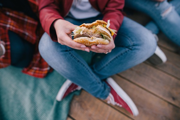 A burger in a woman's hands, with one bite taken