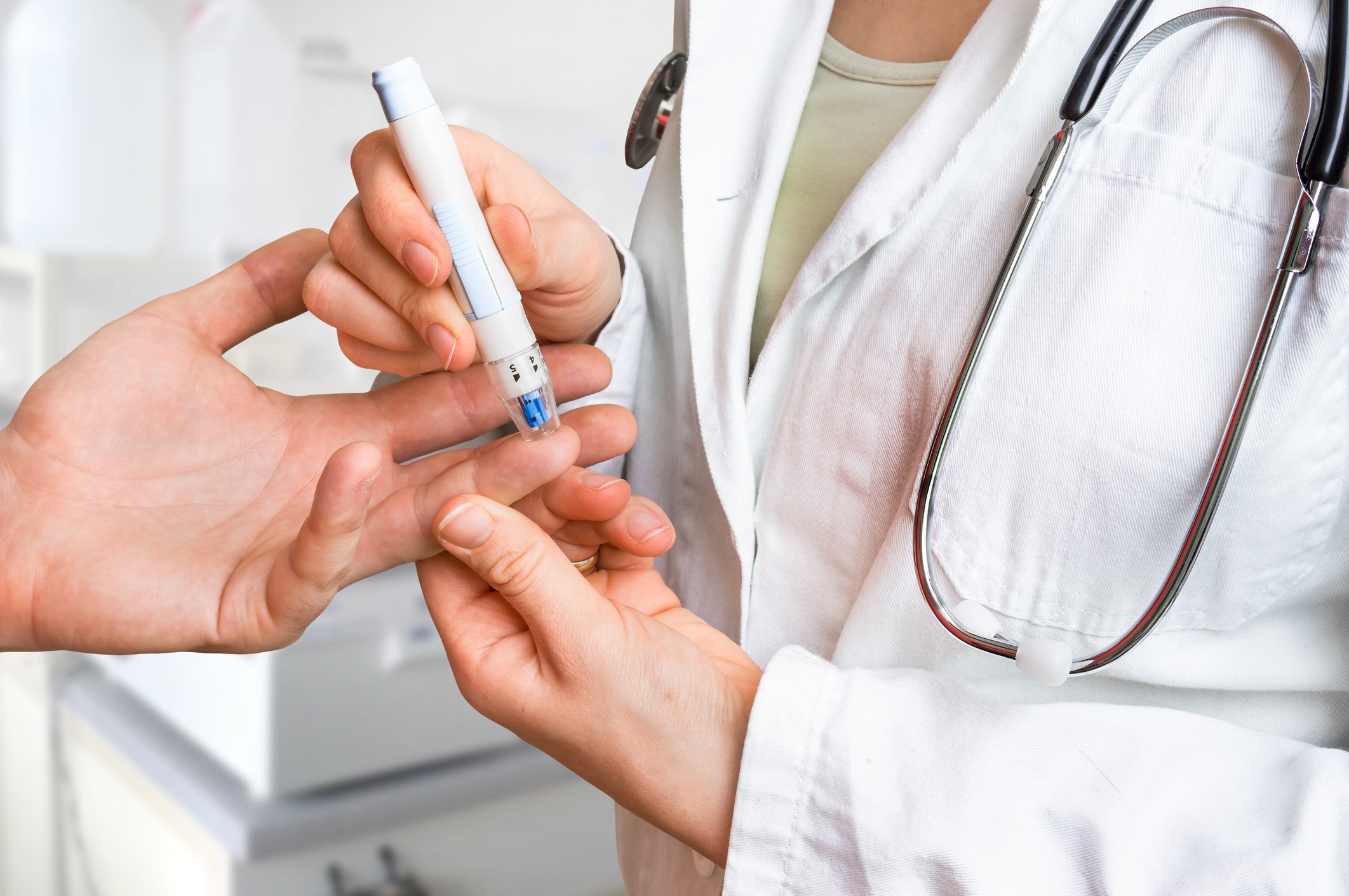 Doctor making a finger stick in patient to test blood