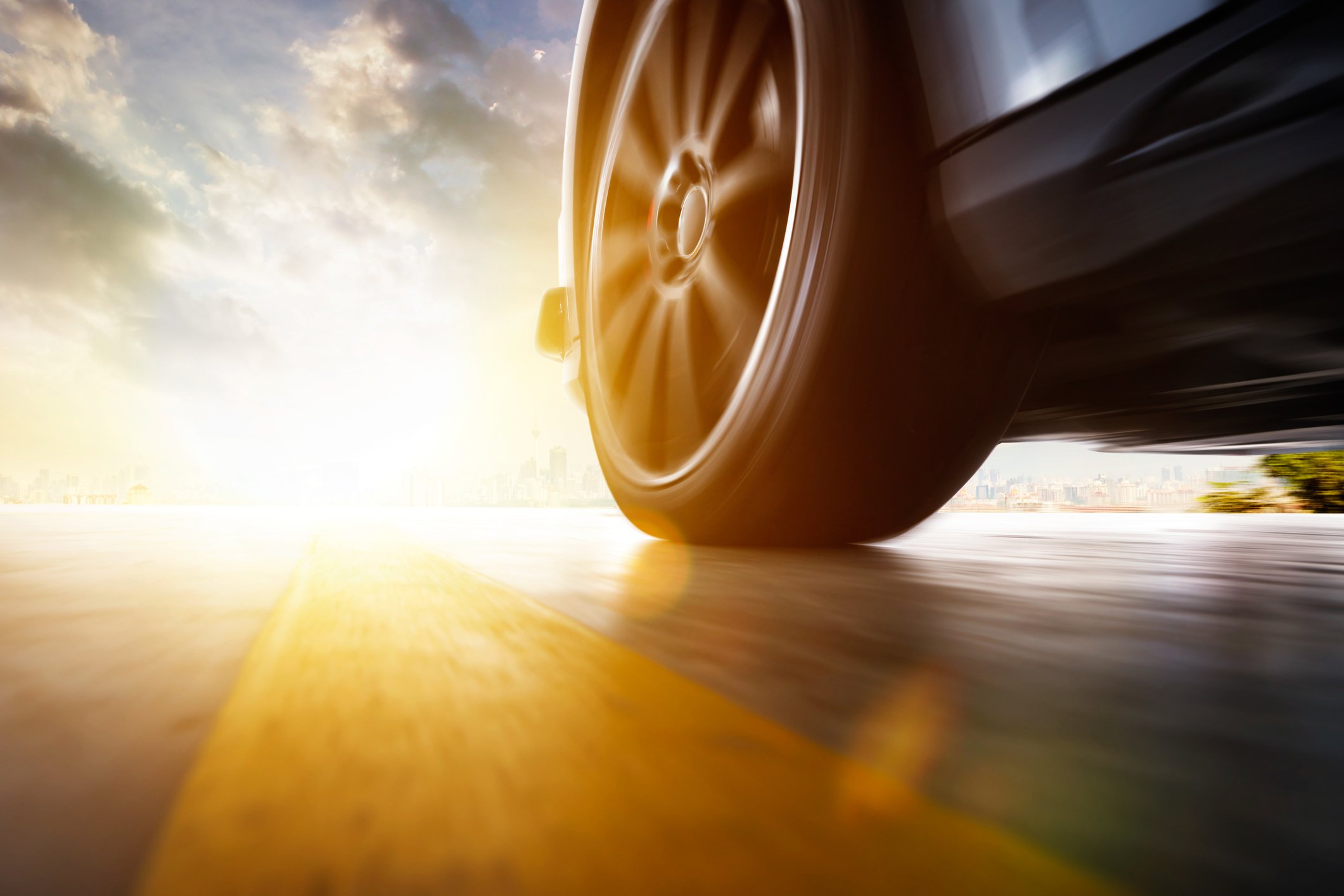 Close-up of car's tire in motion next to yellow line on the road