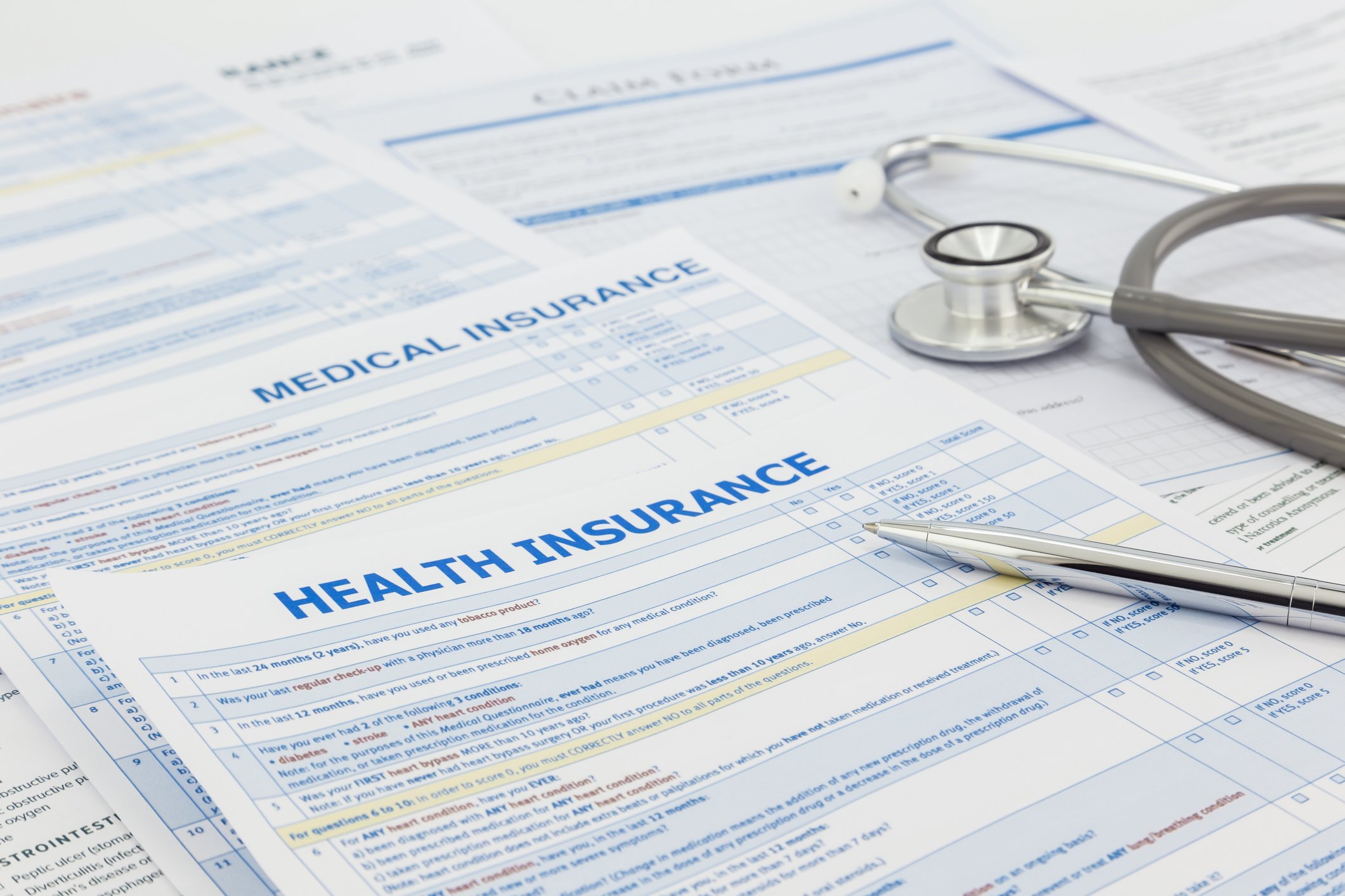 Health insurance forms with stethoscope and pen laying on top