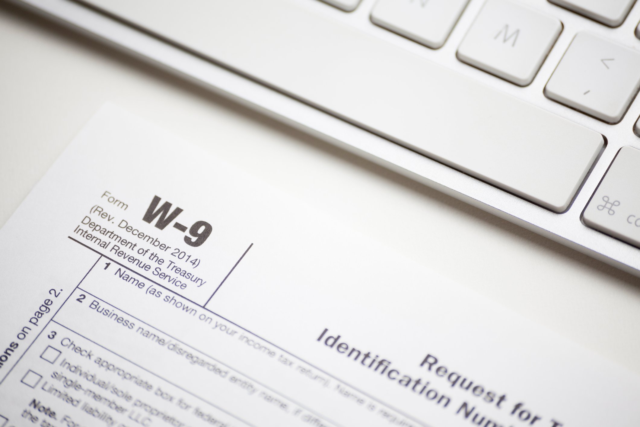 A W-9 form sitting on a desk in front of a keyboard
