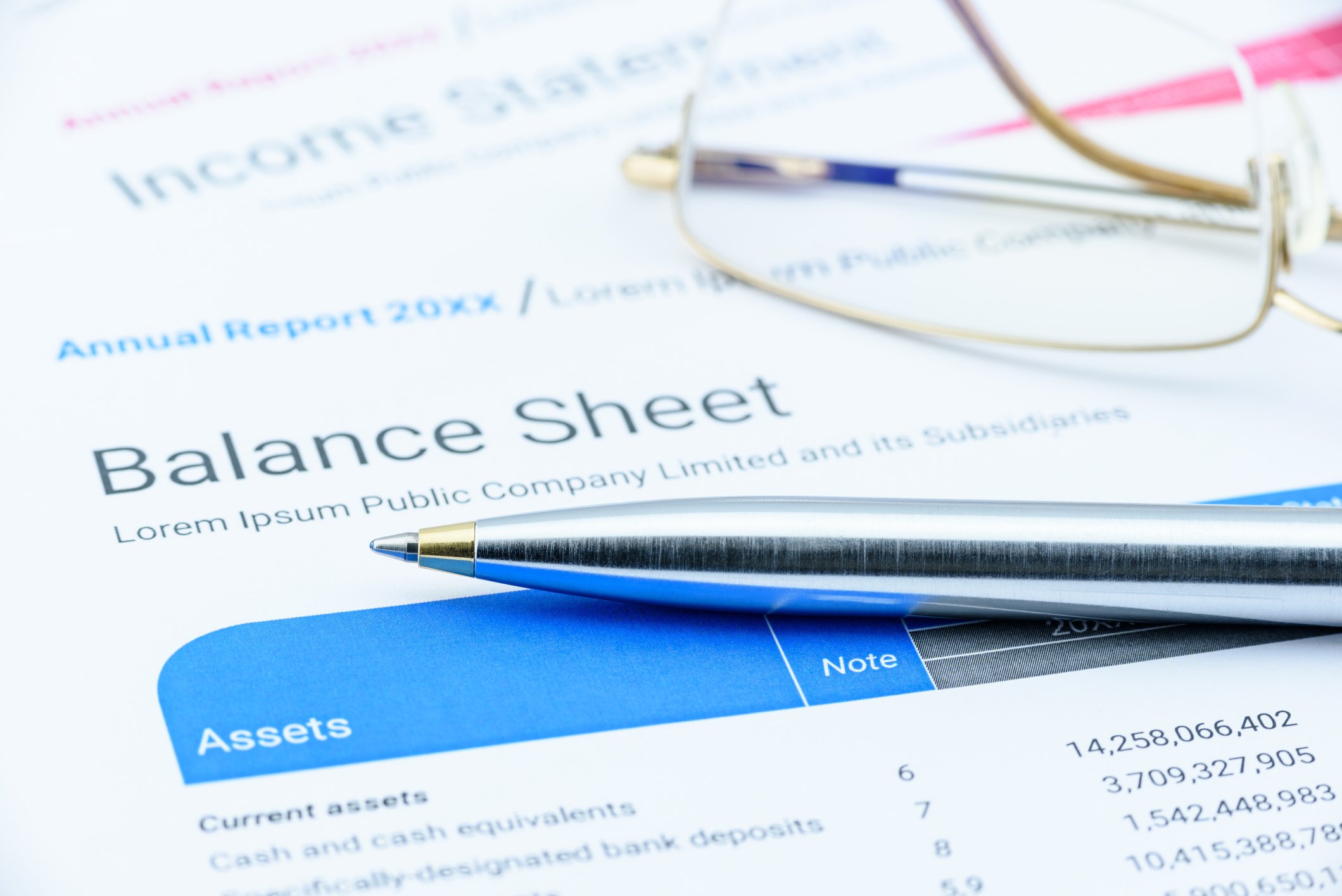 A balance sheet with eyeglasses and a pen lying on it.