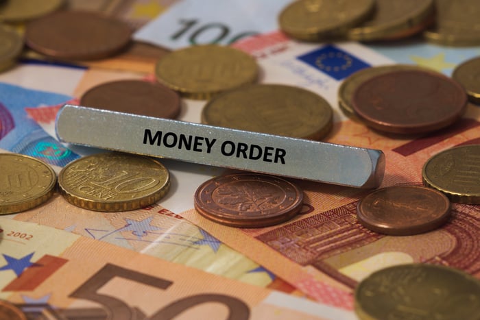 How Do Money Orders Work The Motley Fool - a mental bar reading money order sits on top of scattered coins and bank