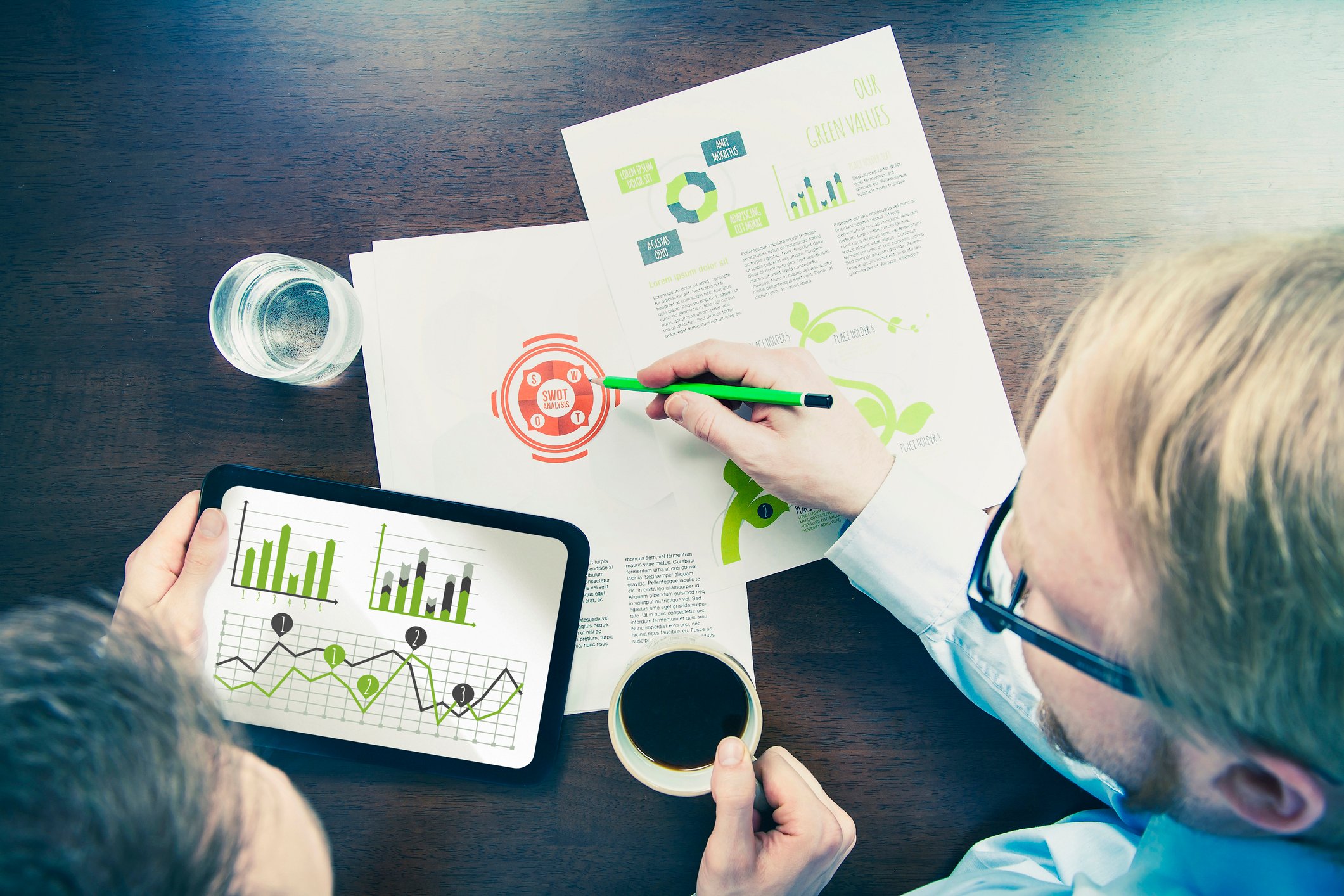Top-down view of two people meeting some with financial graphs and a tablet in front of them