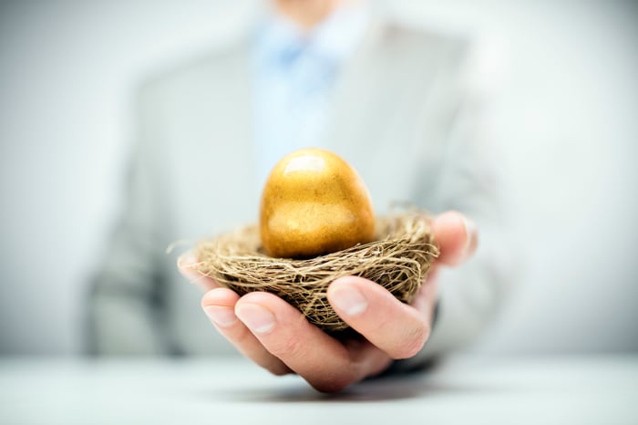 Man in suit holding nest with golden egg in it