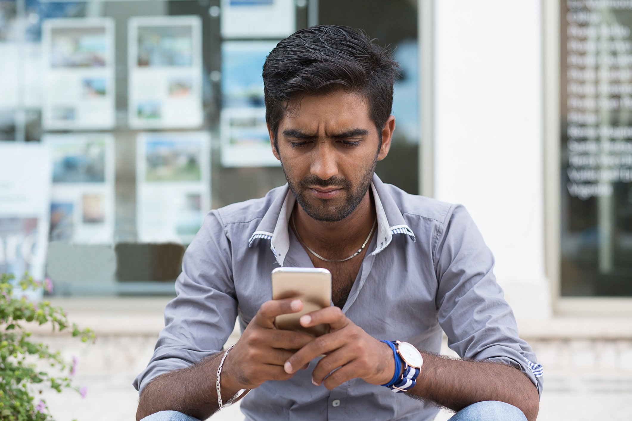 A man sits down and looks at his phone.